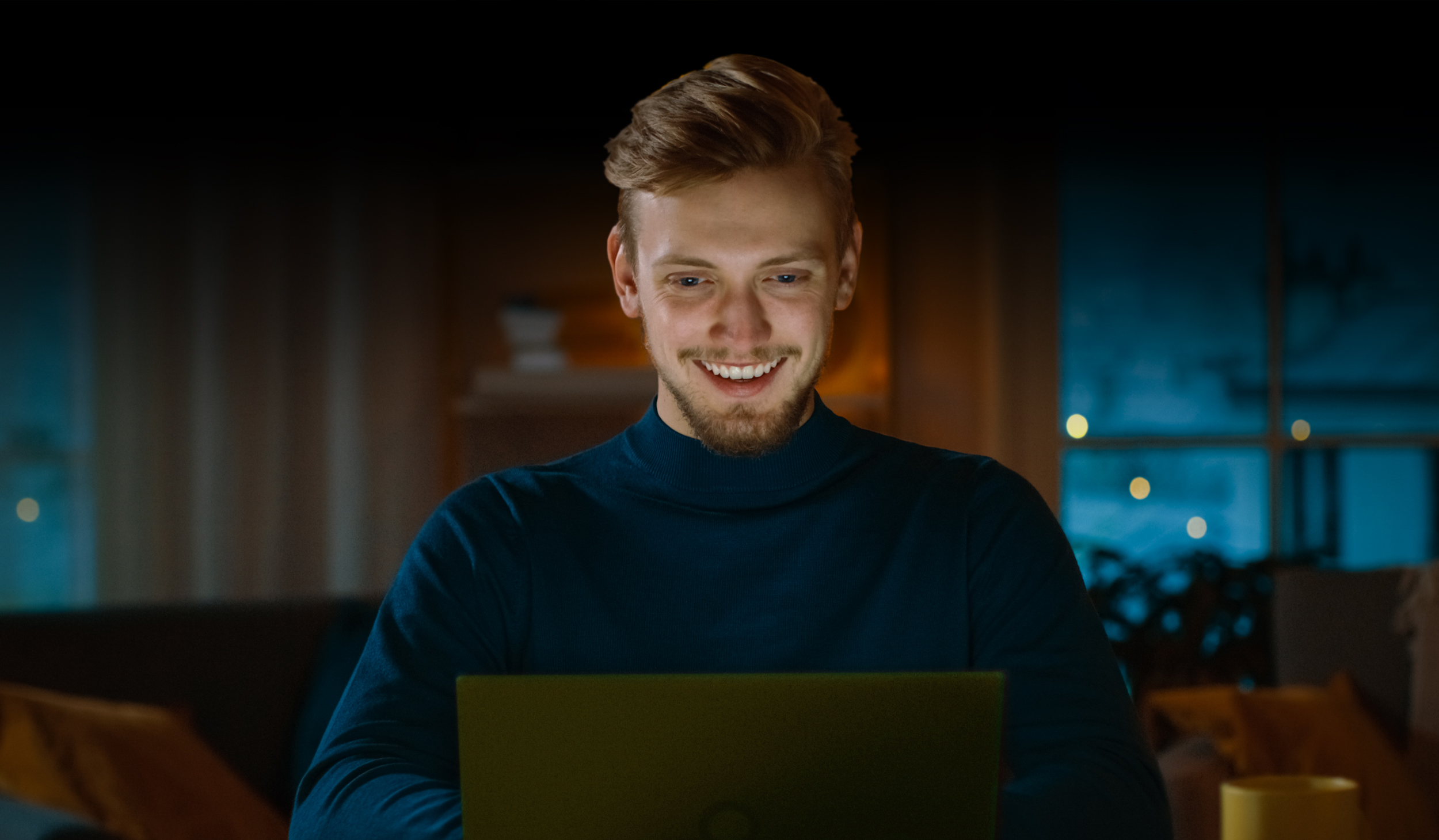 Man smiling sitting behind Windows laptop.