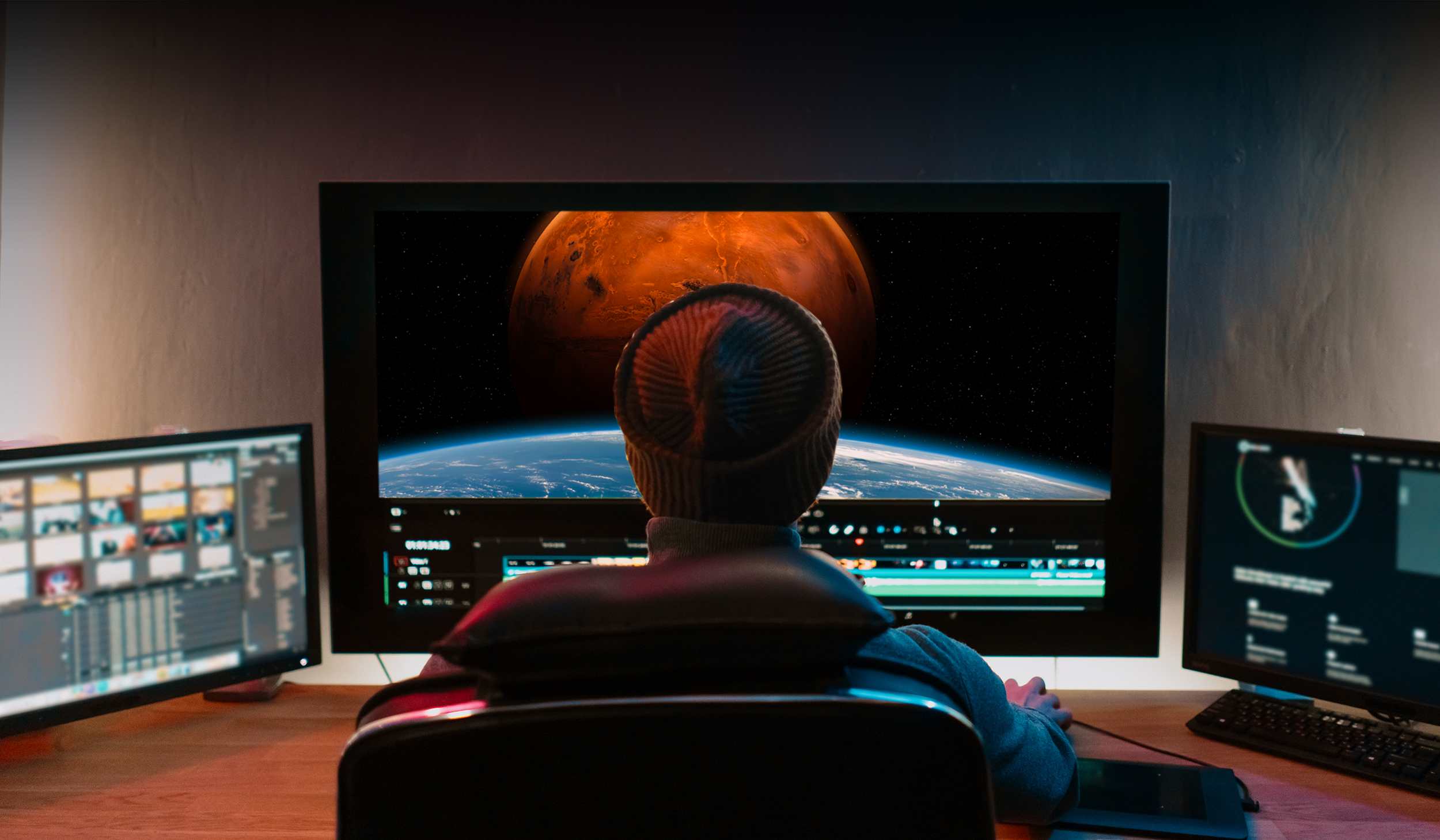 Video editor sitting behind multiple screens.